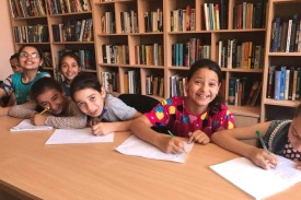 seven young children at a table in a library in Palestine